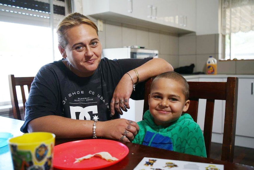 A woman wearing a blue shirt with a boy in a green jumper