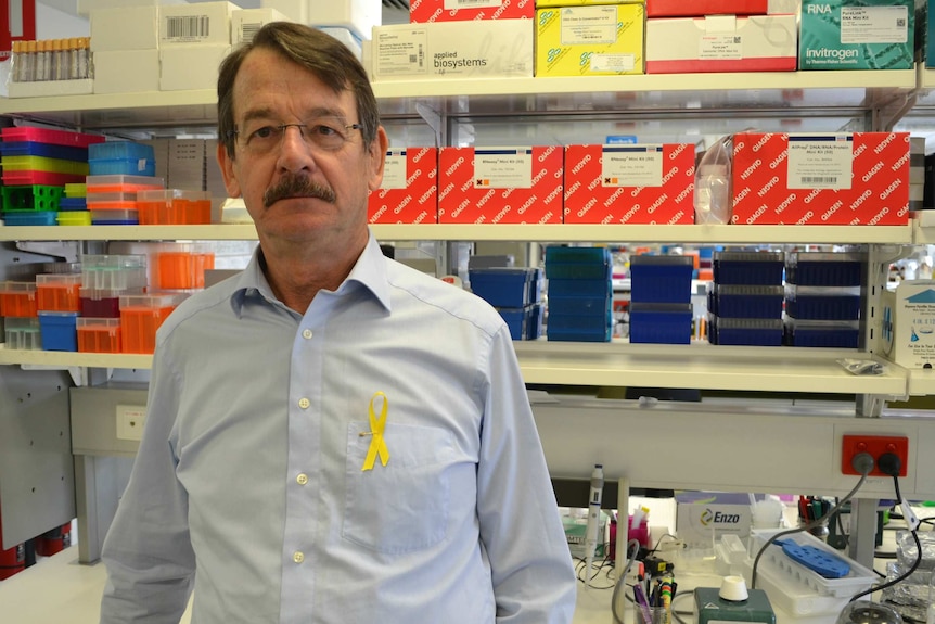 Professor Peter Rogers stands in front of shelves holding containers.