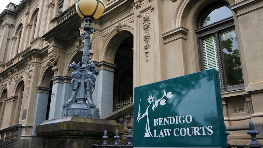 A photo of a signboard with the words "Bendigo Law Courts" in front of a late 19th century Gothic building.