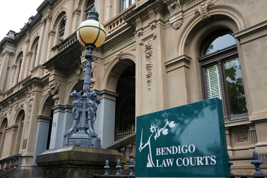 A photo of a signboard with the words "Bendigo Law Courts" on it in front of a late 19th Century Gothic building.