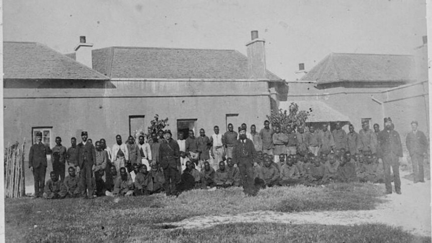 Old photo of men and guards standing outside Rottnest Prison
