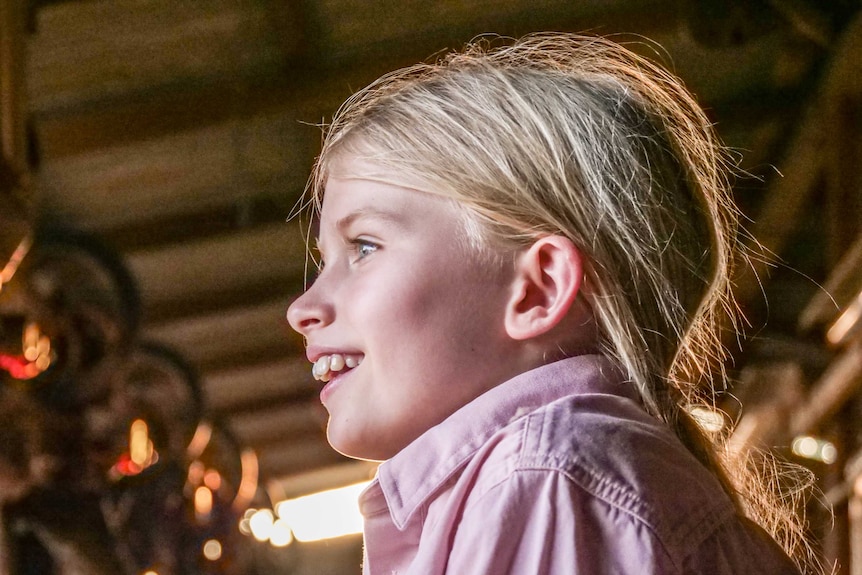 A young girl stares out the side of the picture smiling.