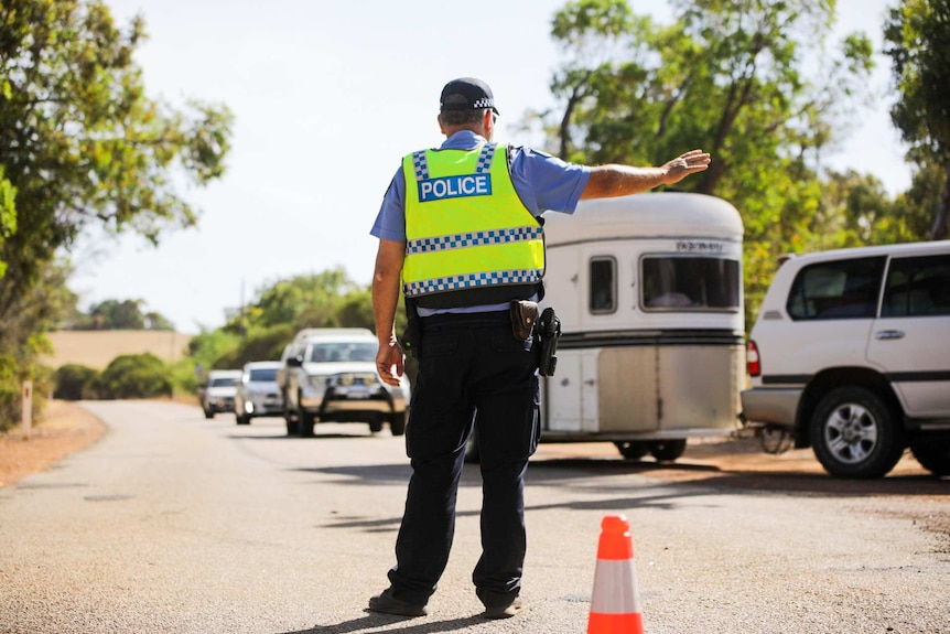 A police officer directs traffic on a road in WA.
