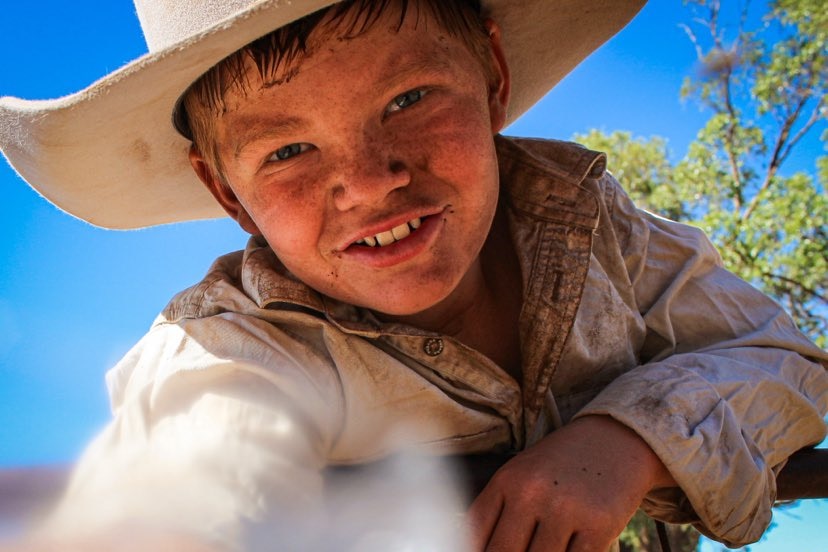 Young boy looking down the barrel of the camera in a cowboy hat
