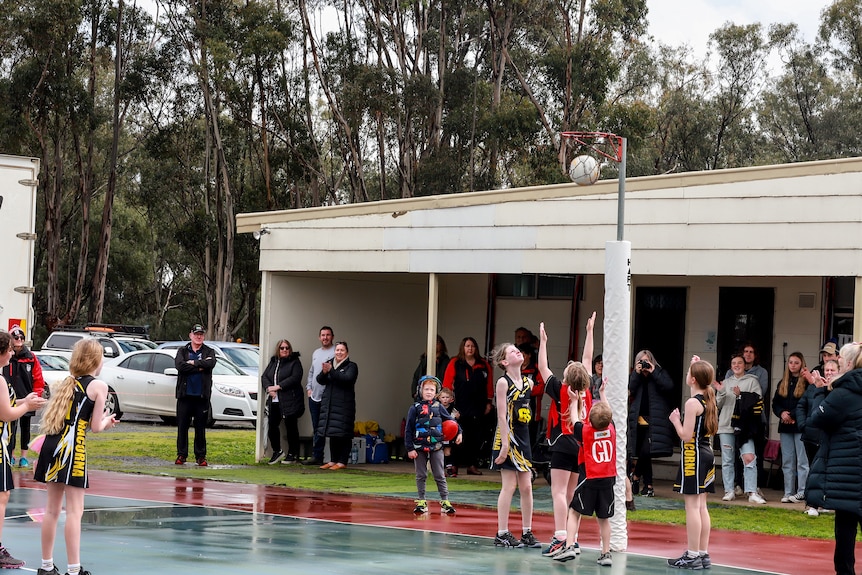 Children playing netball on an outside court wearing bright coloured uniforms