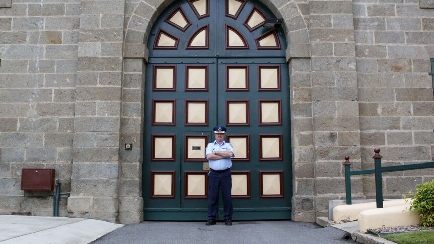 Governor John O'Shea stands outside the tall granite walls of Cooma jail.