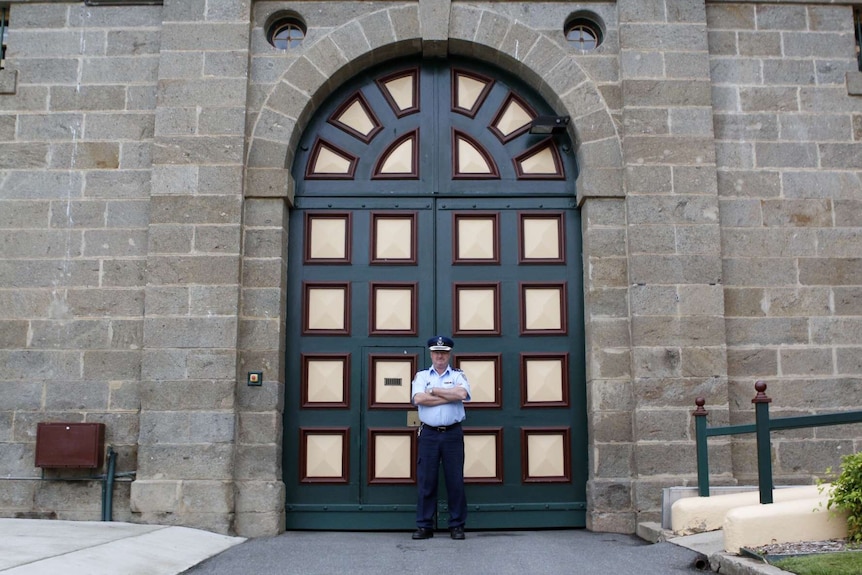 Governor John O'Shea stands outside the tall granite walls of Cooma jail.