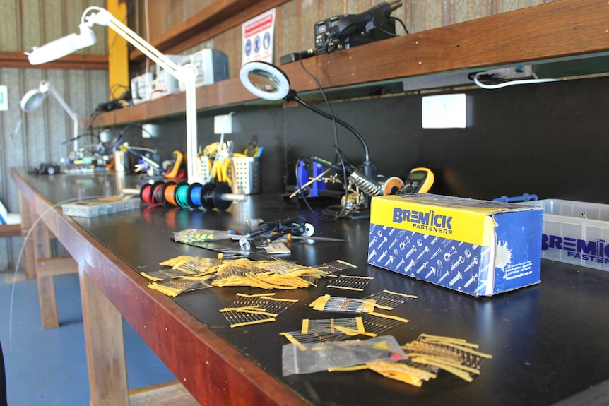 A work bench is filled with tools and equipment used to make robotics