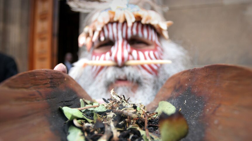 Close up image of Ngarrindjeri man in the process of conducting a traditional Smoking Ceremony