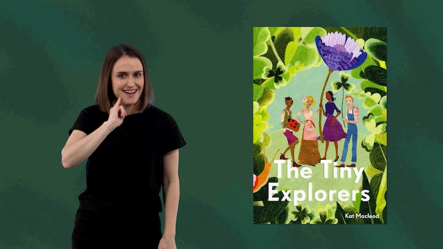 Auslan presenter Julia Murphy stands beside image of book, The Tiny Explorers