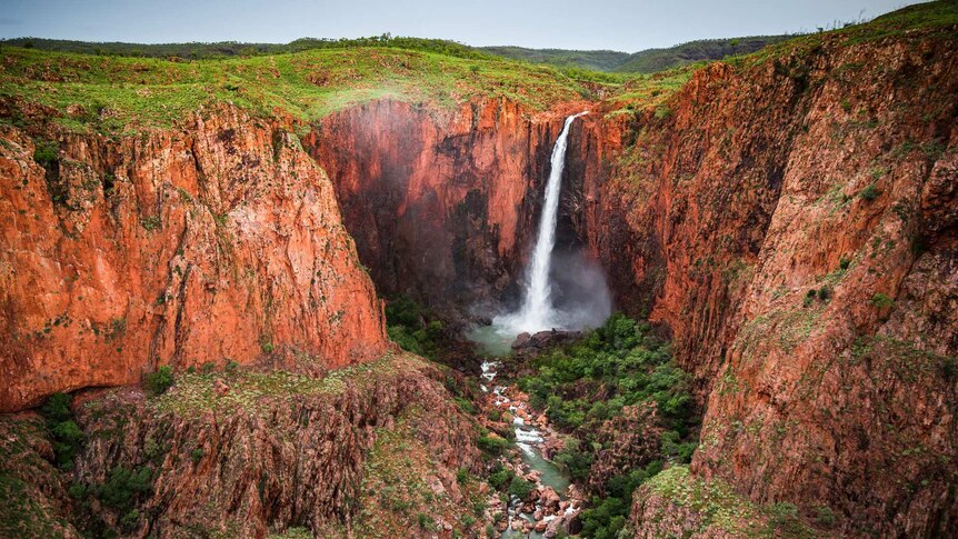 Waterfall over gorge of deep red rock