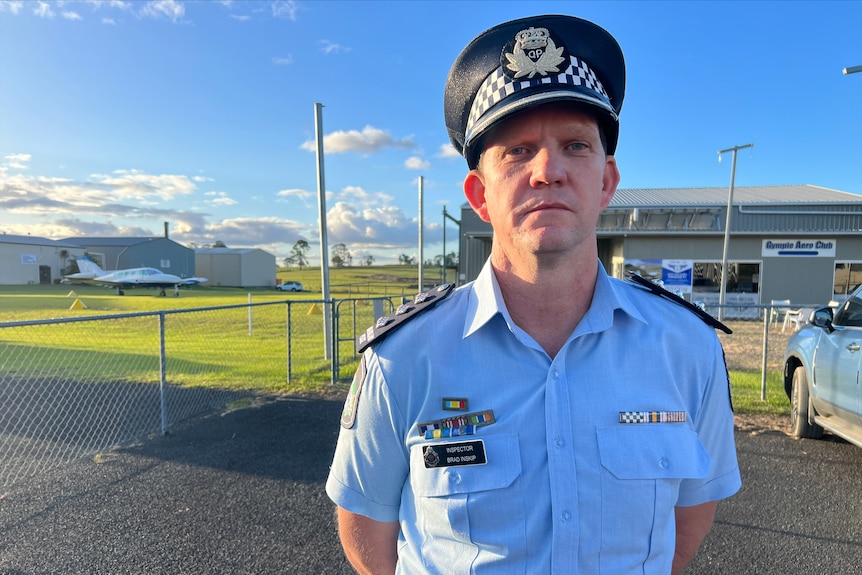 A police officer in uniform stands outside an airport.