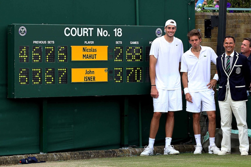 Two tennis players — one smiling, one frustrated — pose next to a scoreboard at Wimbledon.