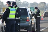 Three police officers at a coronavirus checkpoint on a highway.