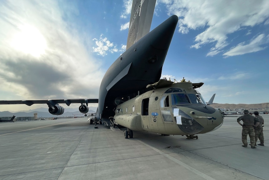 A helicopter being loaded on to a carrier plane. 