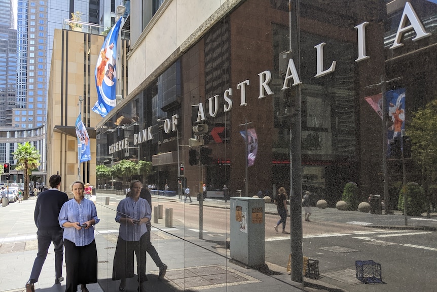 Жена и мъж минават покрай централата на Резервната банка на Австралия в Сидни.