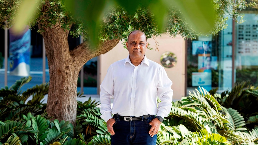 Man stands in front of trees 