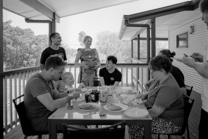 A group of people eating breakfast on a deck. 