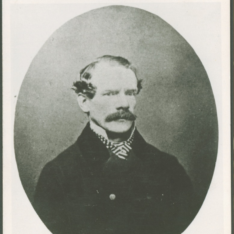 An historic portrait photo showing a moustachioed man in a jacket and cravat.
