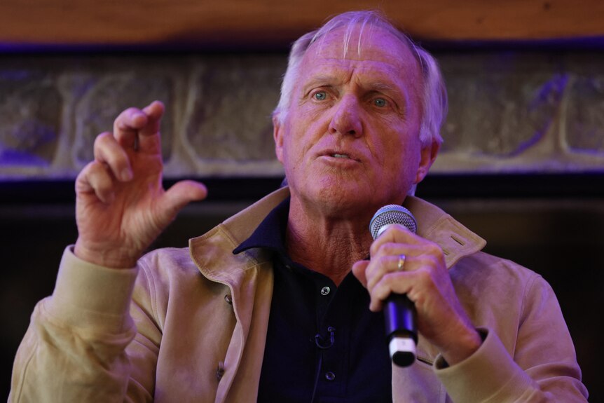 Greg Norman speaks with a microphone.