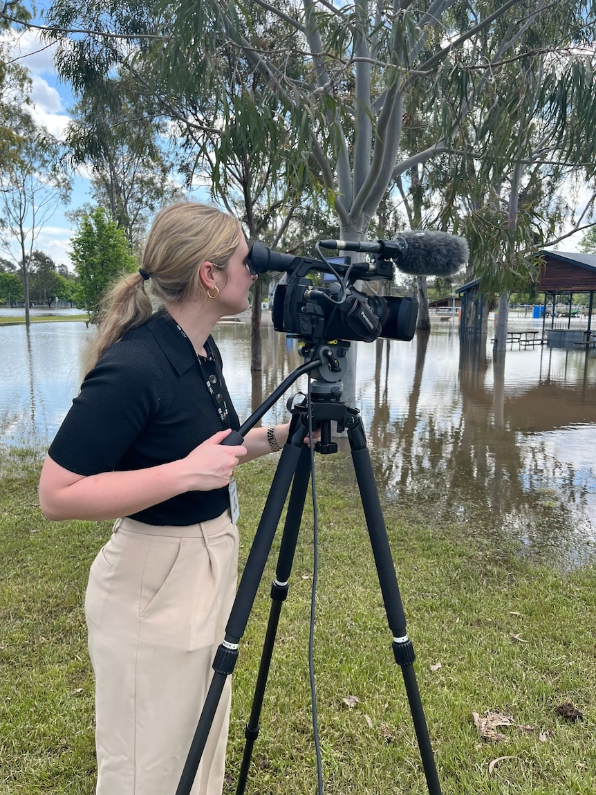 Woman filming floods with a camera on a tripod.