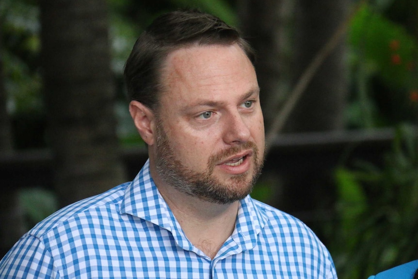 Adrian Schrinner, wearing a check shirt, speaks.