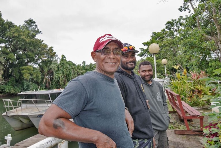 Man with a cap and glasses smiles at the camera.