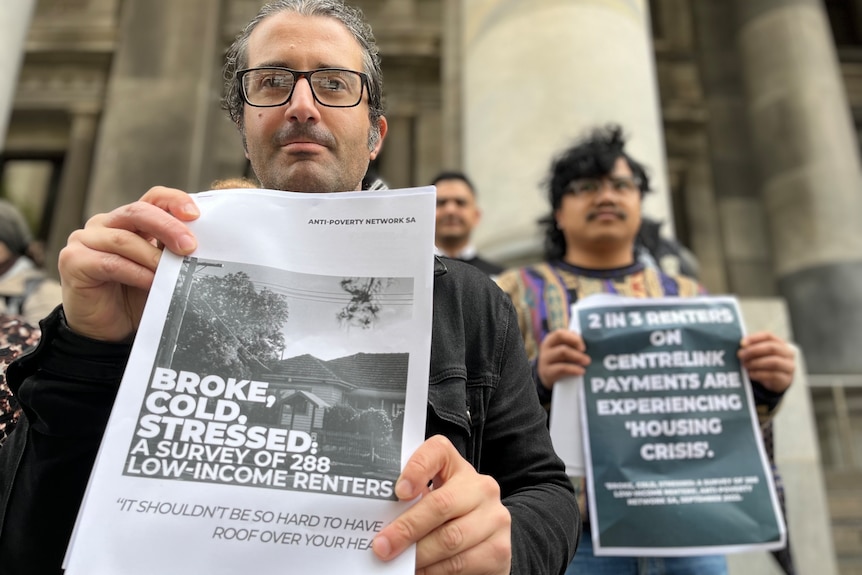 Two men protesting with signs that detail the hardship renters face 