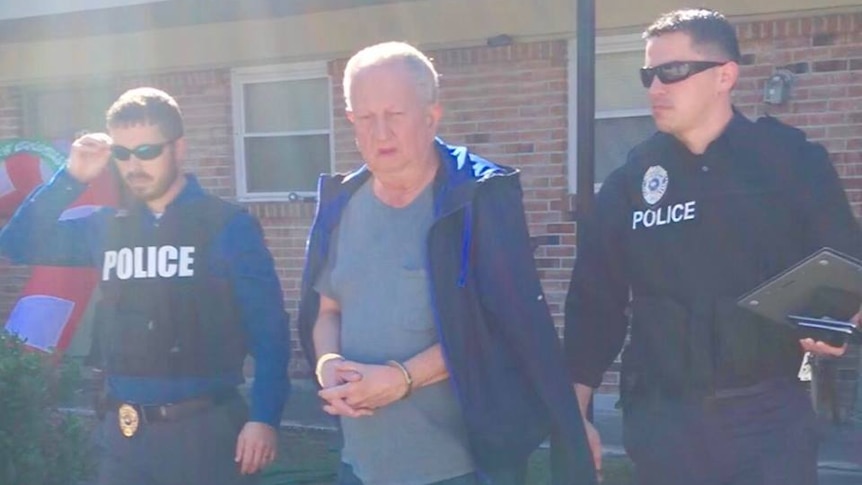 Police lead a handcuffed 67-year-old man out of a house.