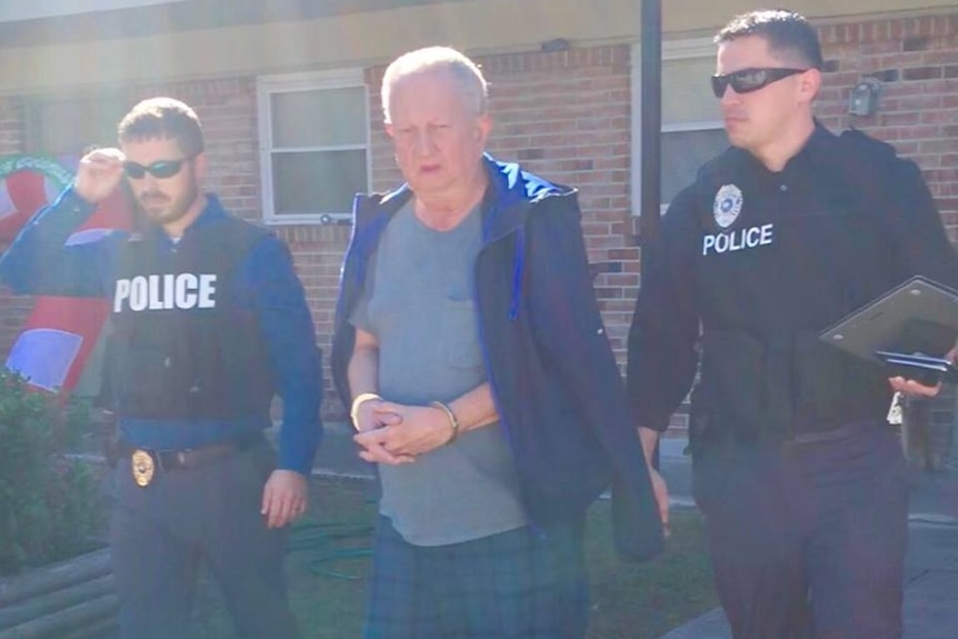 Police lead a handcuffed 67-year-old man out of a house.