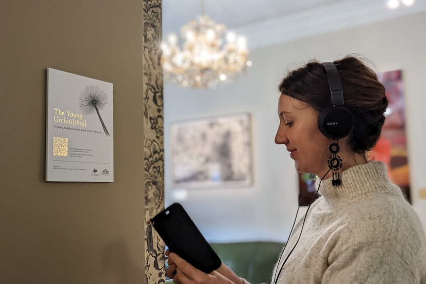 a woman is wearing headphones and looking at her phone