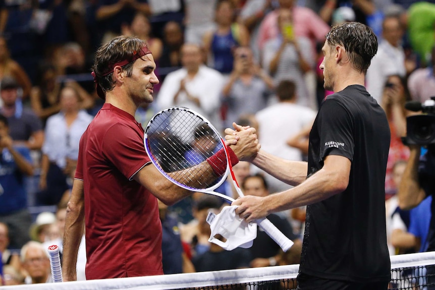 Roger Federer shakes hands with John Millman at the net.