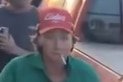 man in red cap and green shirt pictured with cigarette hanging from his mouth 