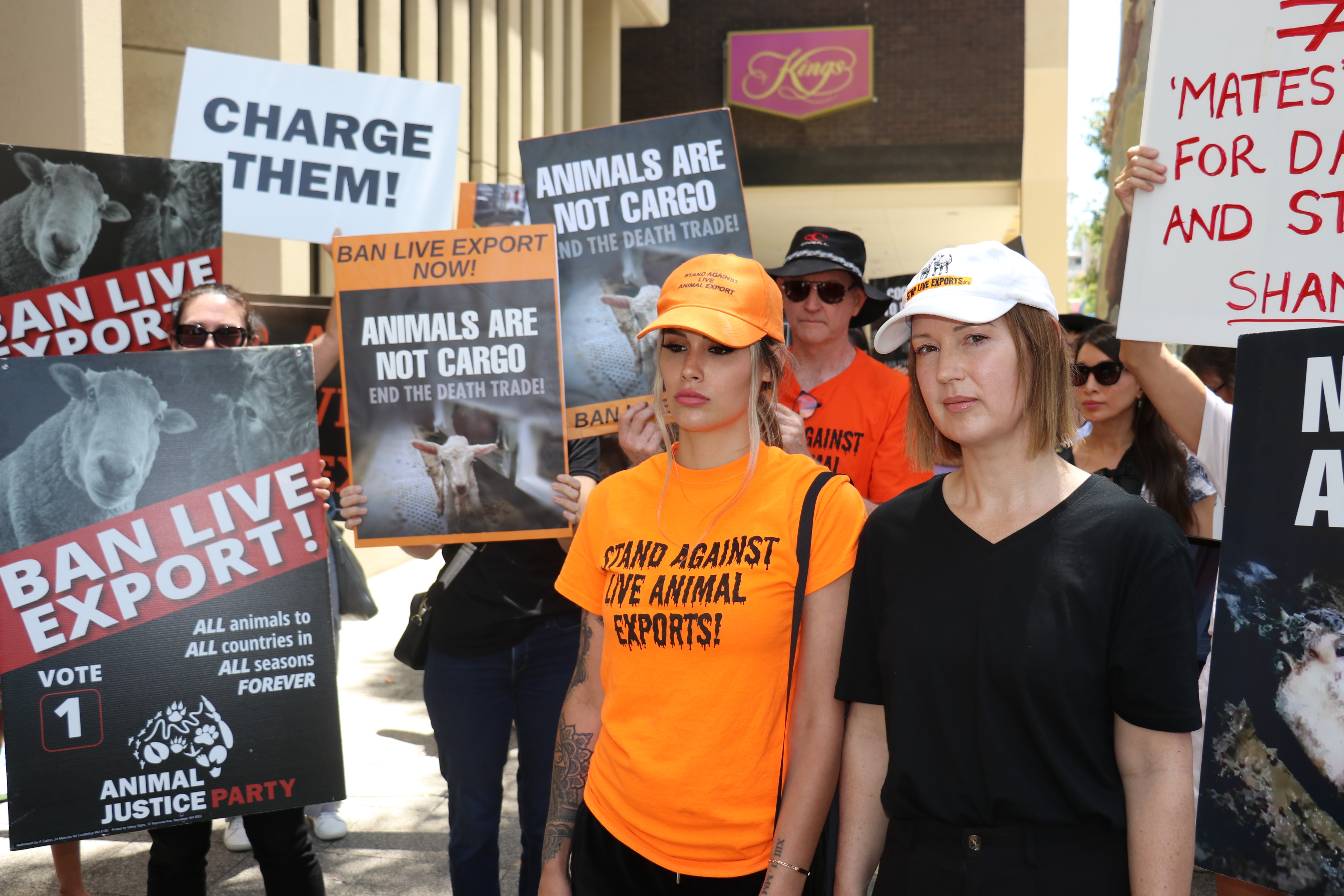 Two women stand in front of a bunch of people picketing