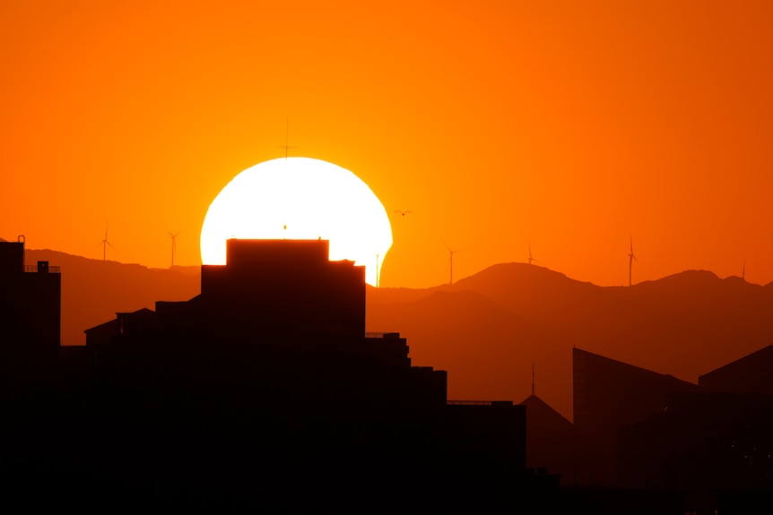 The sun is partially eclipsed as it sets over the horizon in Beijing