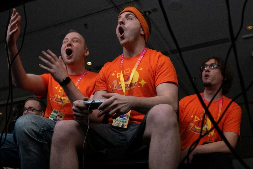 Three gamers celebrate while playing Super Mario Brothers.