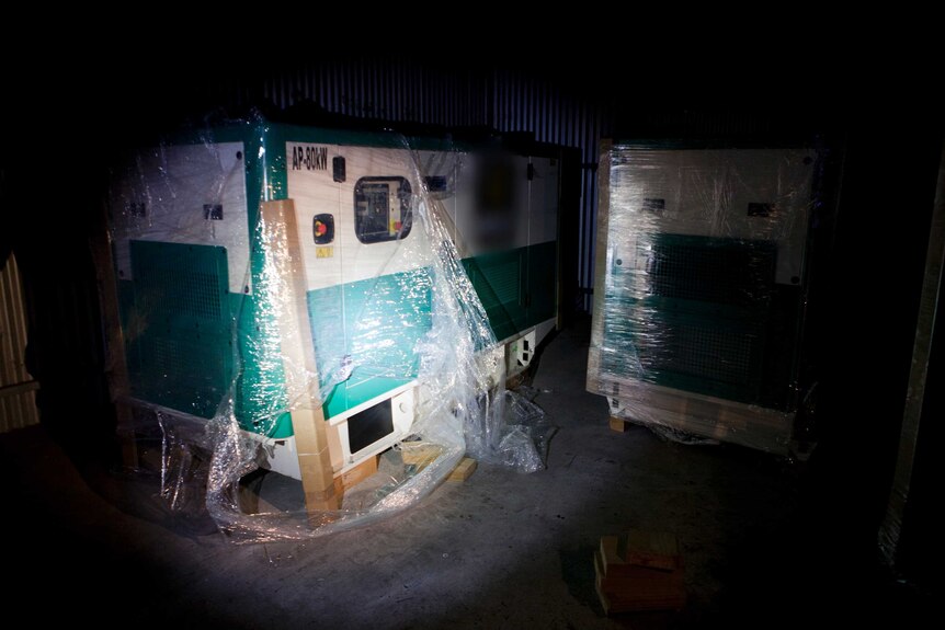 Two large diesel generators wrapped in clear plastic.