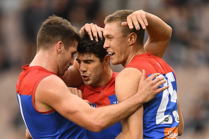 Jesse Hogan, Christian Petracca and Tom McDonald of the Demons react to a goal against Carlton.