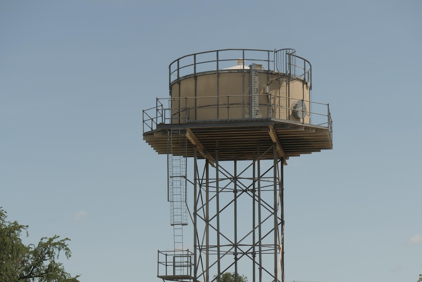 A metal water tower against a bright sky. 