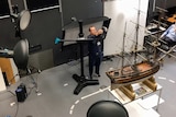 Dr McCarthy is holding a camera taking a scan of a model ship