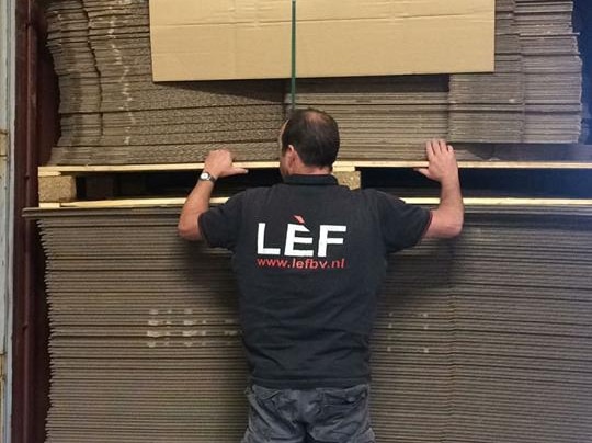 The inside of a back of a truck with lots of cardboard boxes, which will be made into tents, flattened down.