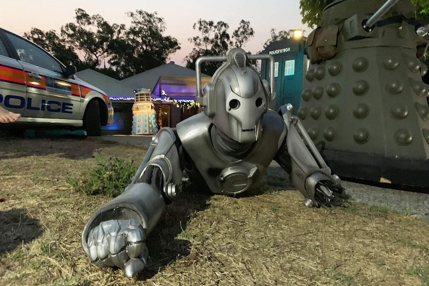 Half a cyberman crawls on groud with Doctor Who TARDIS and dalek in front yard of home at Ipswich, west o Brisbane.
