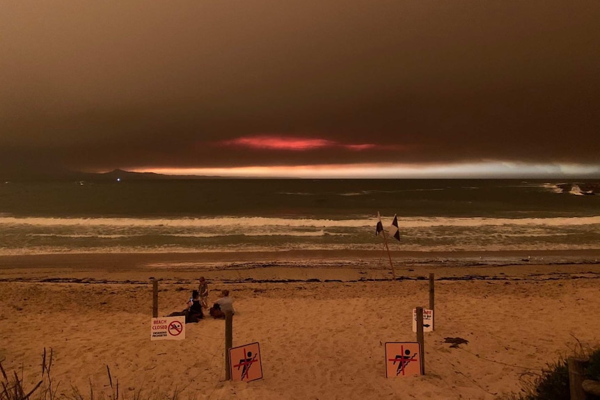 A beach underneath a dark orange sky.