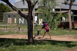a young aboriginal woman pushing a baby in a pram