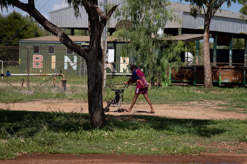 a young aboriginal woman pushing a baby in a pram