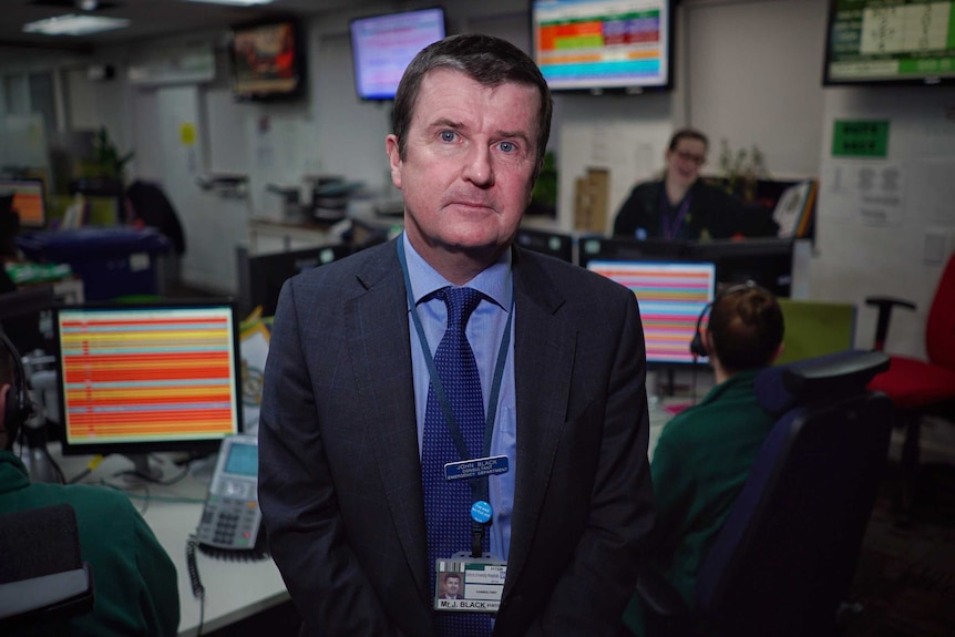 Dr John Black looks at the camera as he stands in a hospital.