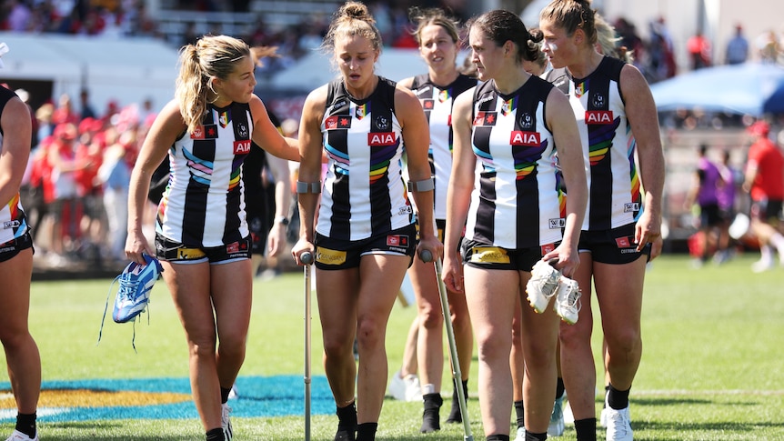 Ruby Schleicher looks disappointed and is on crutches as teammates walk alongside her