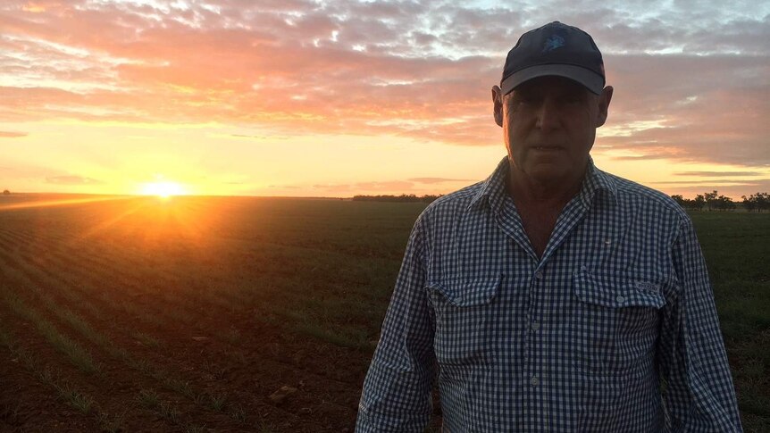 Farmer on property with sunset in the background.