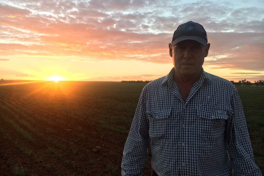 Farmer on property with sunset in the background.