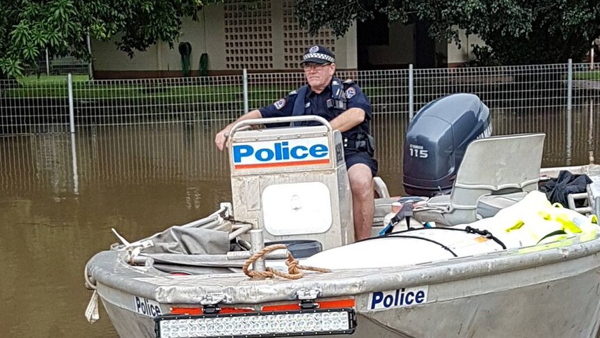 A policeman on a police boat on a flooded street.